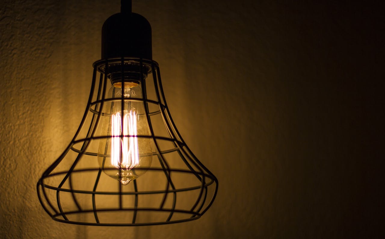 Close-up of a vintage Edison bulb inside a wire cage fixture casting warm light.